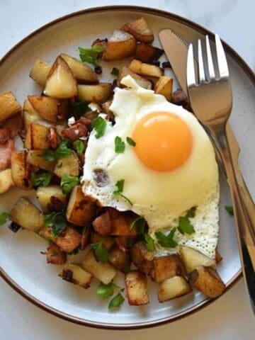 Pyttipanna on a plate with cutlery on the side.