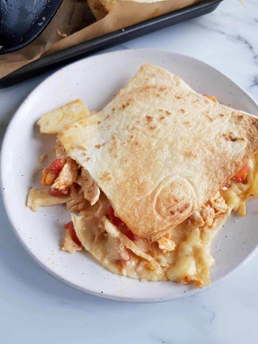 Sheet pan buffalo chicken quesadillas on a plate on a marble table.