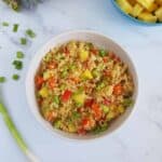 Tropical pineapple fried quinoa in a bowl on a marble table.