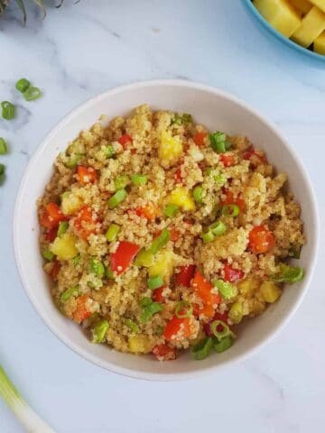 Tropical pineapple fried quinoa in a bowl on a marble table.