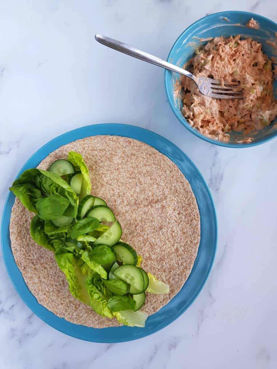 Tuna salad in a bowl, with a tortilla on a plate on the side.