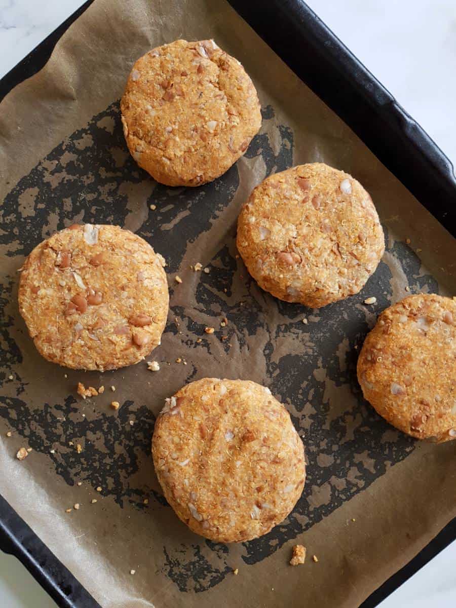 Uncooked pinto bean burgers on a sheet pan.