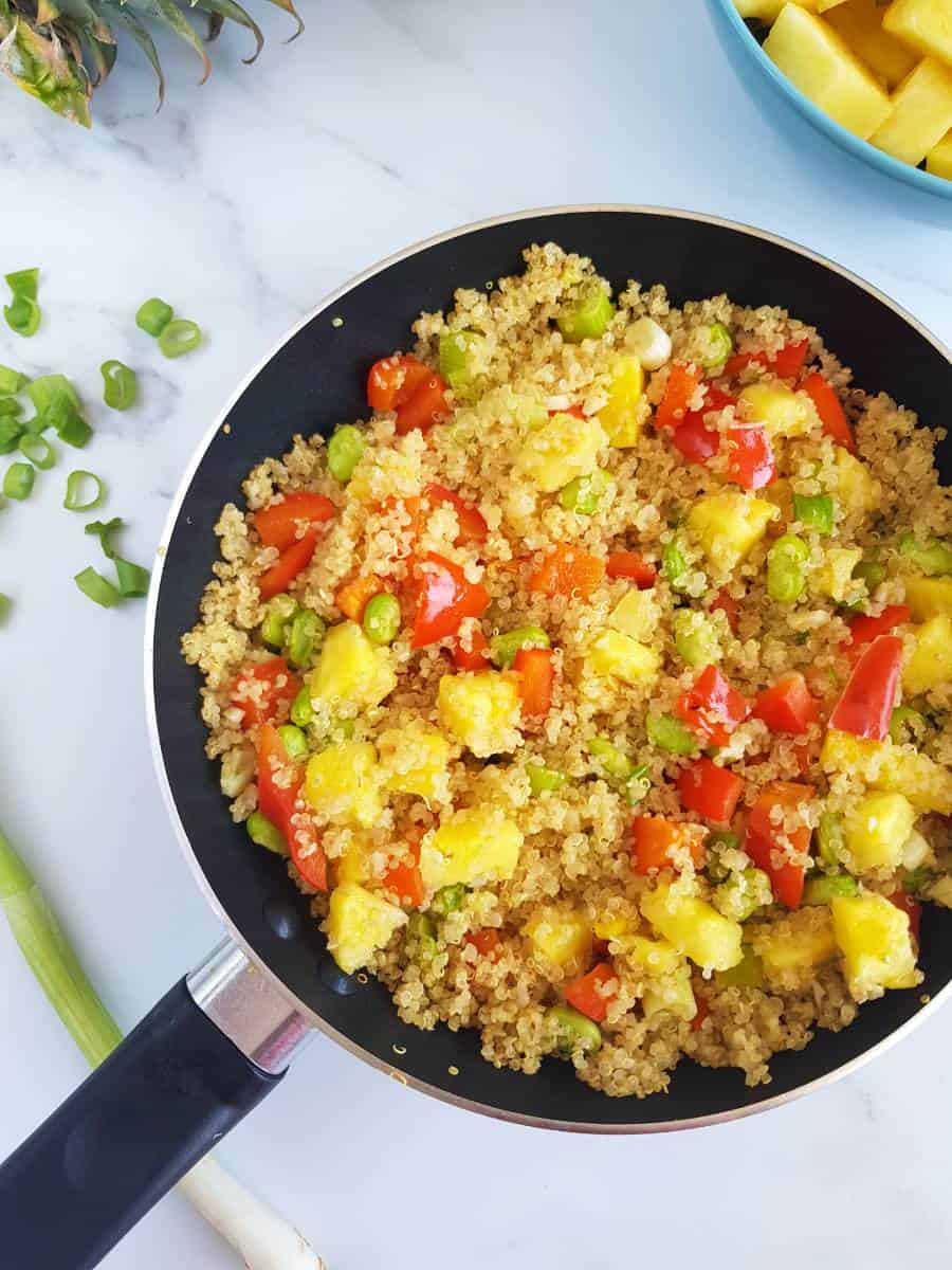 Vegan pineapple fried quinoa in a skillet on a marble table.
