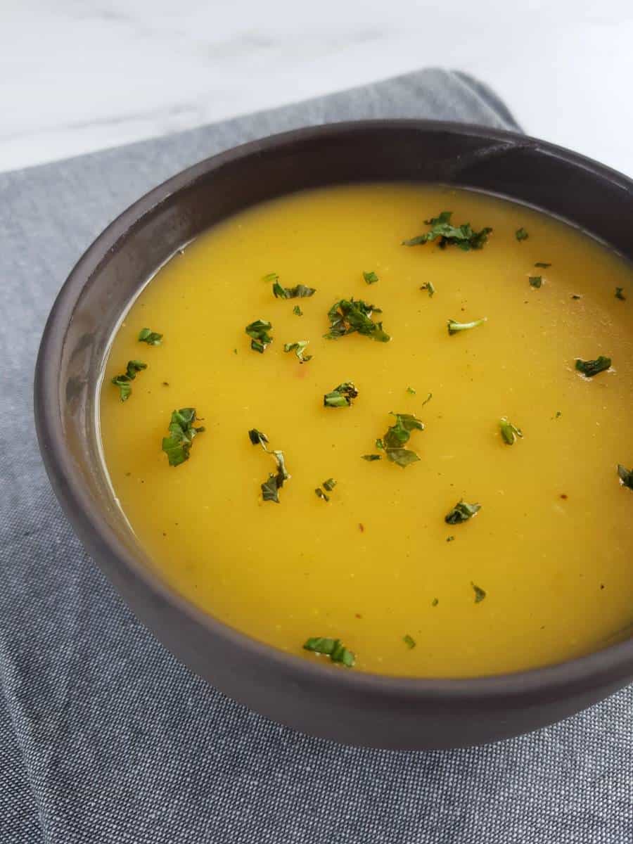 Vegan potato carrot soup topped with fresh herbs.