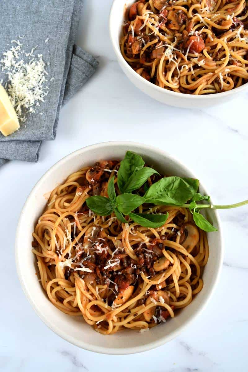 Vegetarian lentil bolognese in bowls with spaghetti and parmesan.