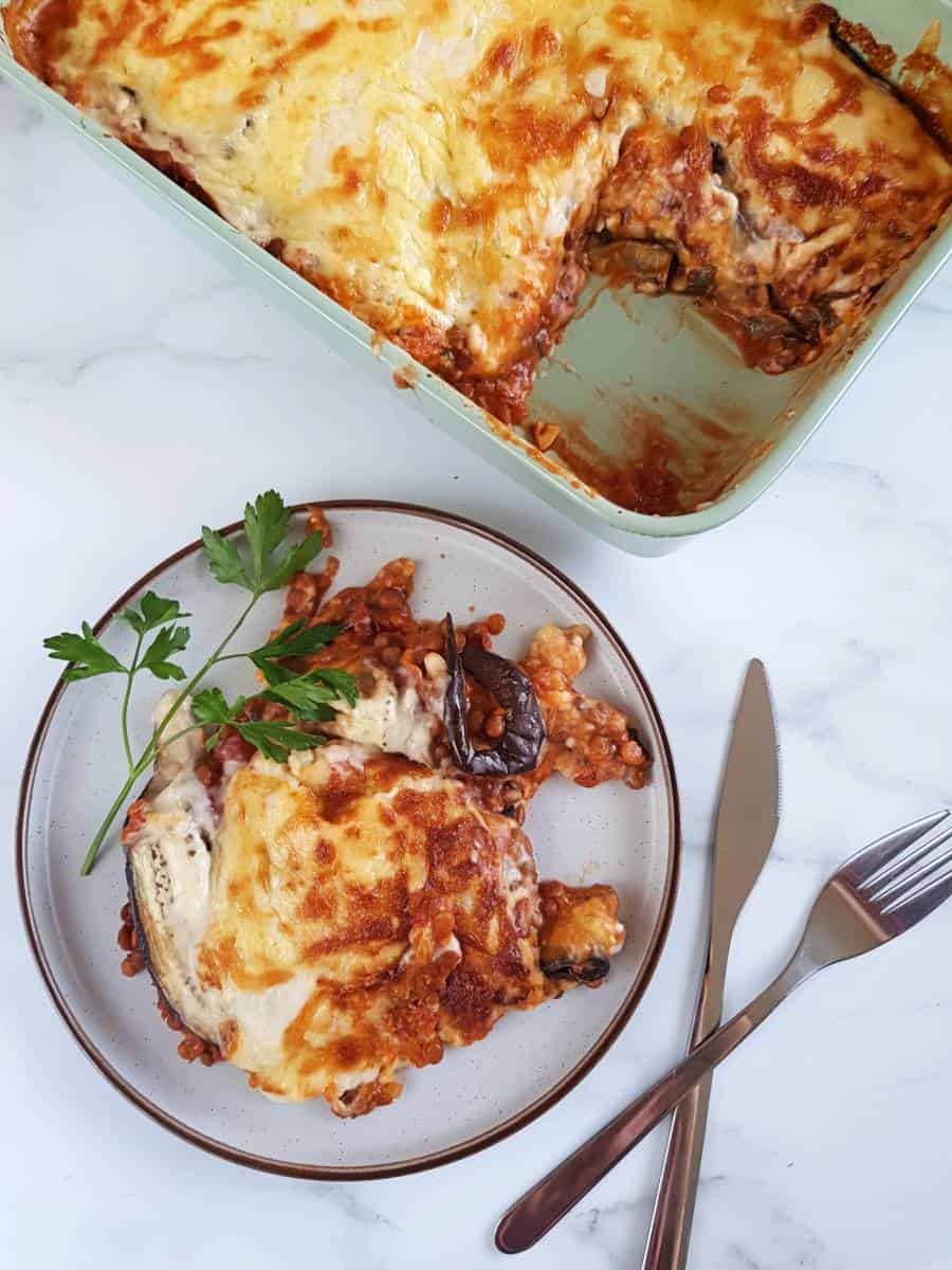 Vegetarian moussaka on a plate with cutlery on the side.