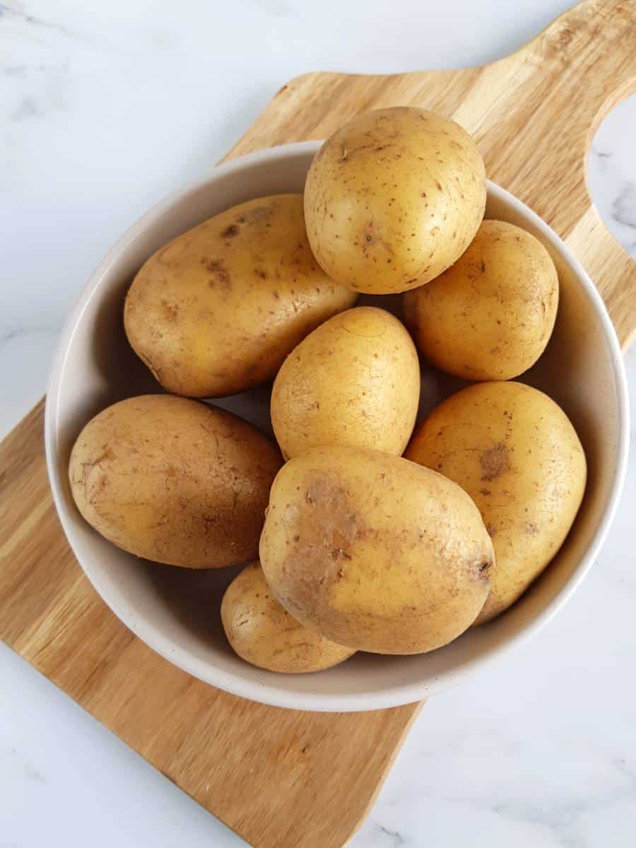 Whole potatoes on a chopping board.