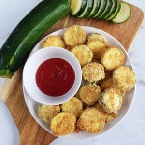 Zucchini breaded slices on a wooden board.