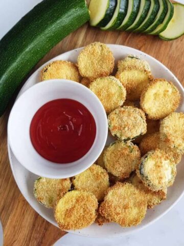 Zucchini breaded slices on a wooden board.