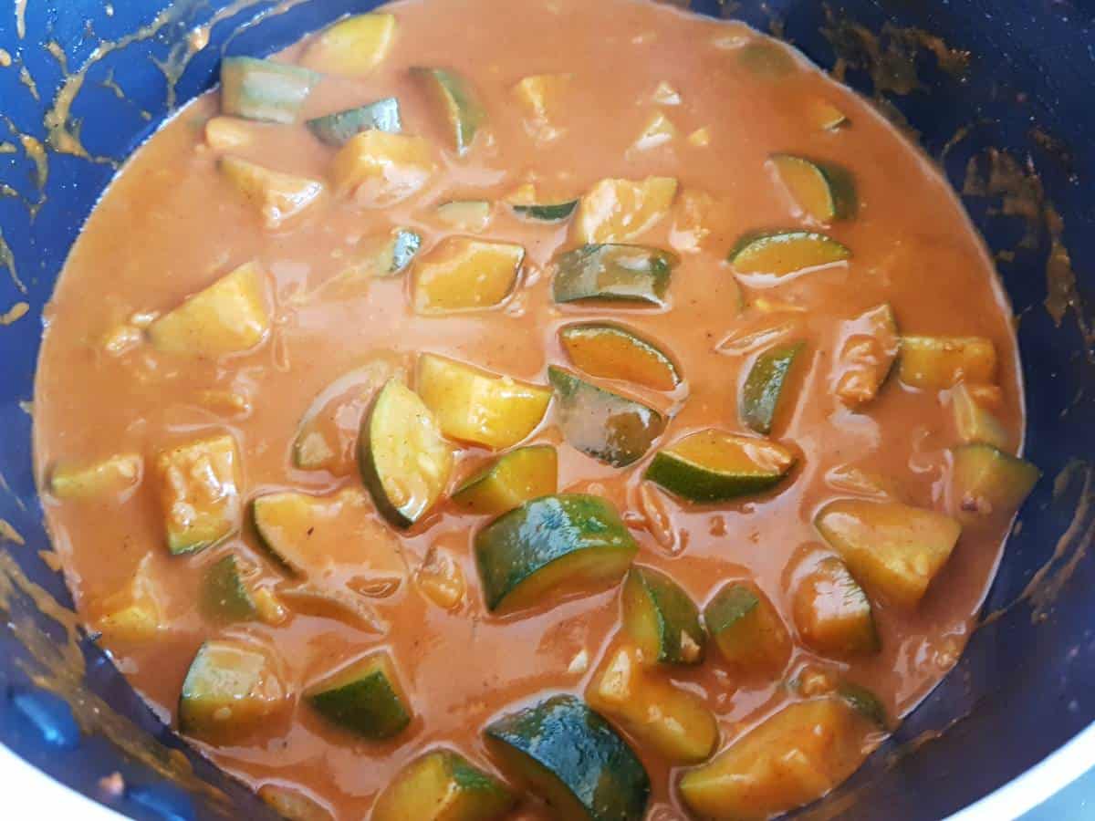 cooking zucchini curry in a pot.