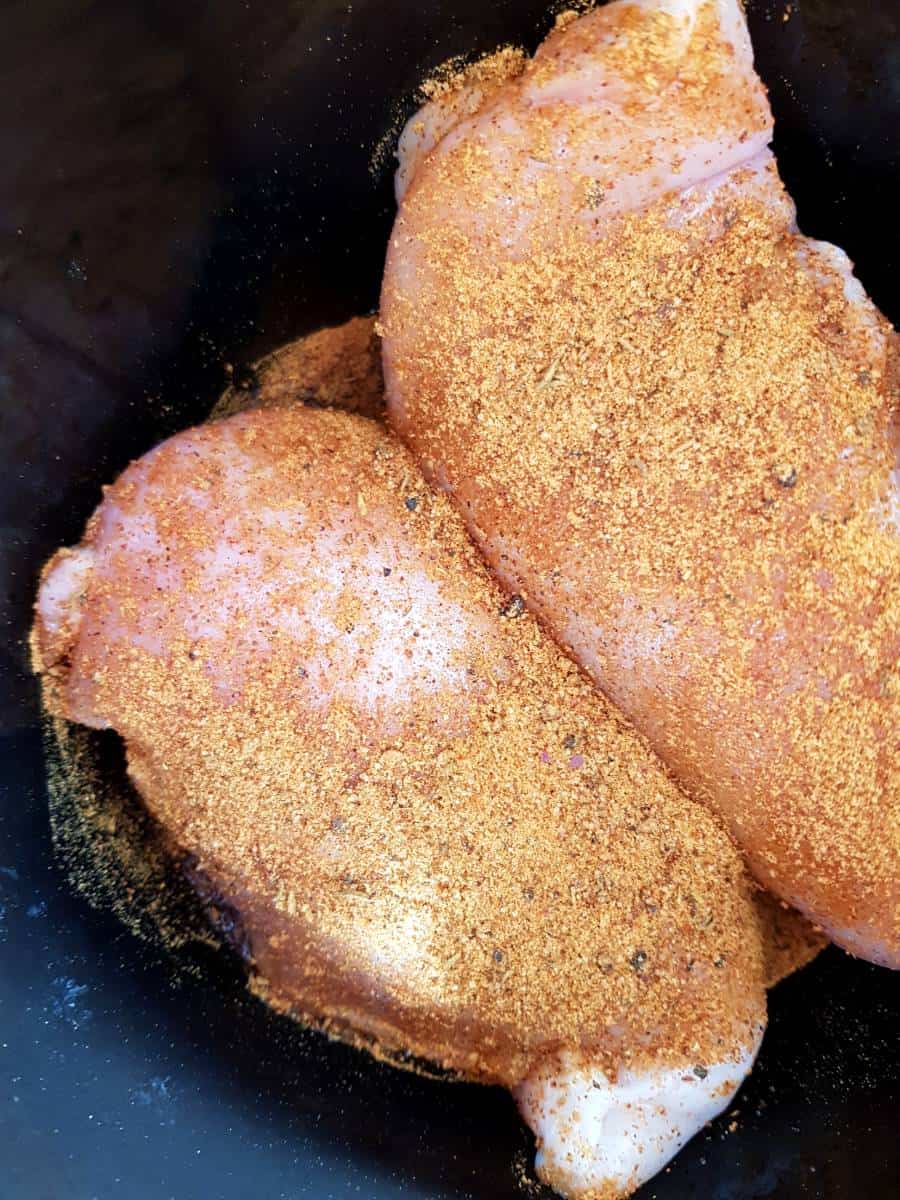 Chicken and cajun seasoning in a slow cooker.