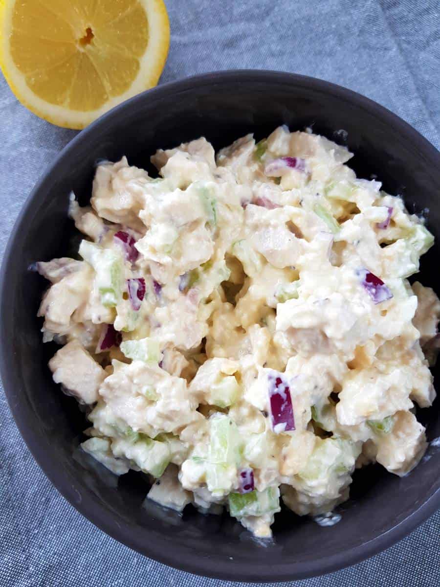 Greek yogurt chicken salad in a bowl with lemon on the side.