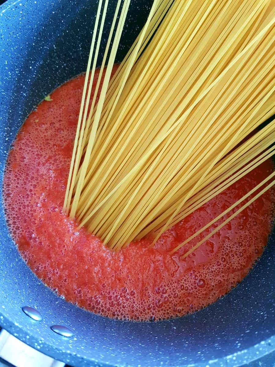 Jollof sauce and spaghetti in pot.