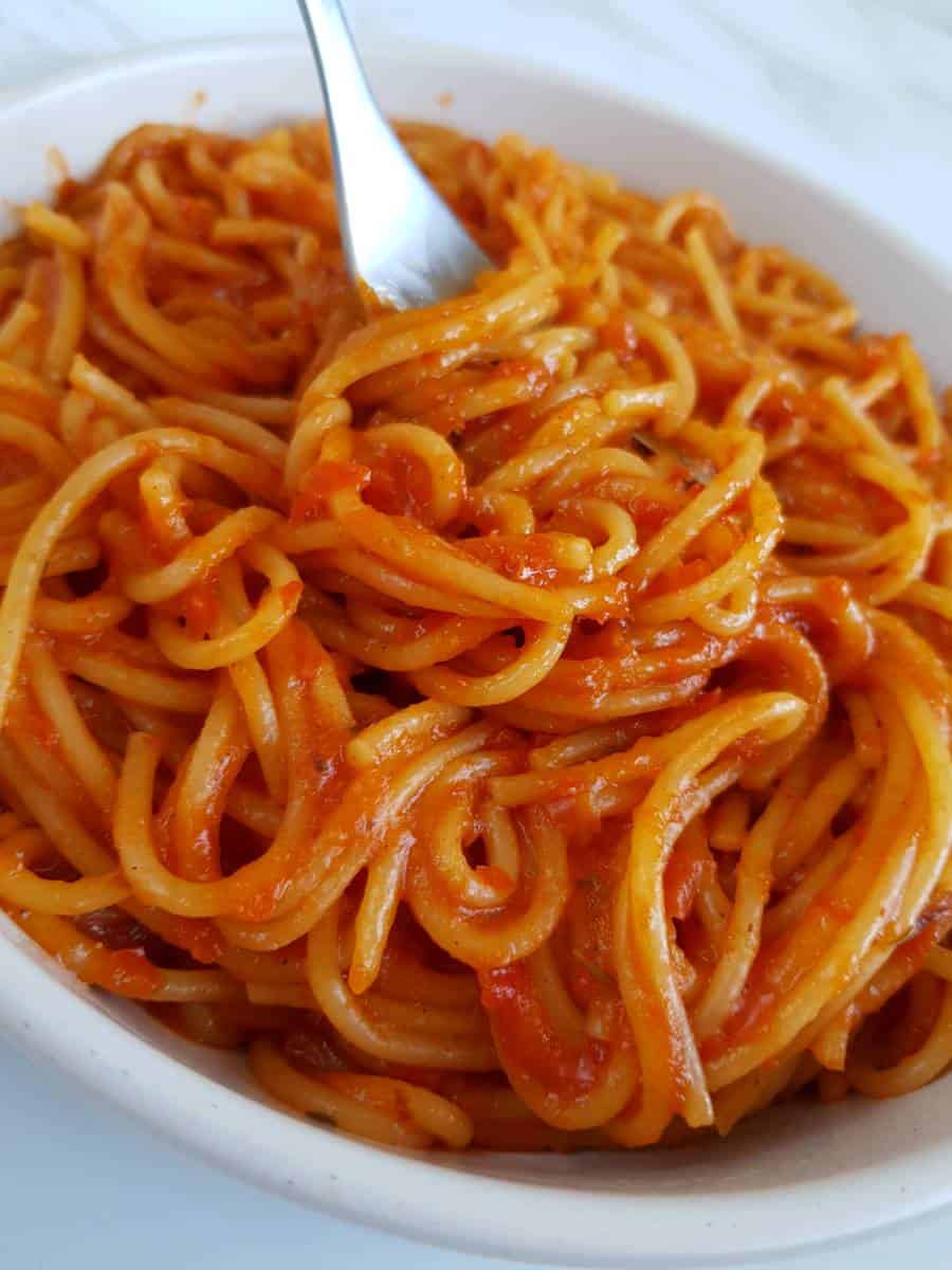 Jollof spaghetti in a bowl with a fork.