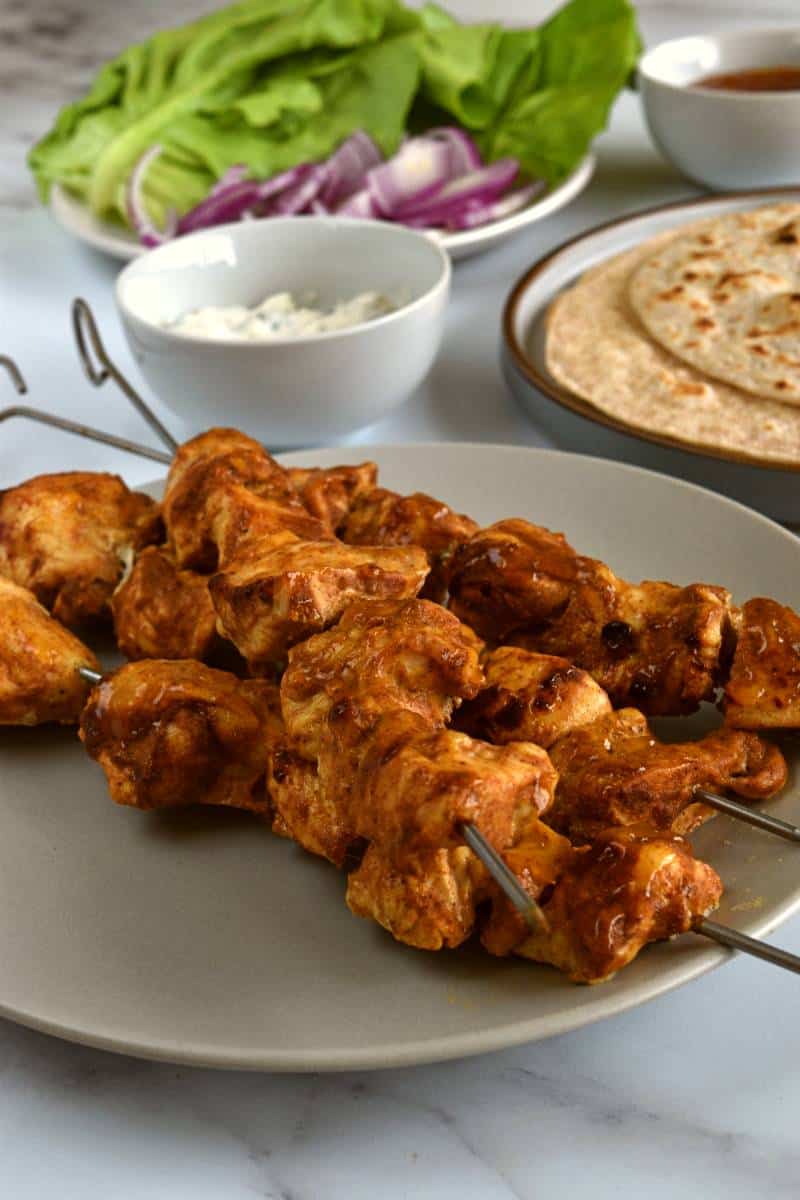 Chicken tikka kebab with lettuce and wraps in the background.