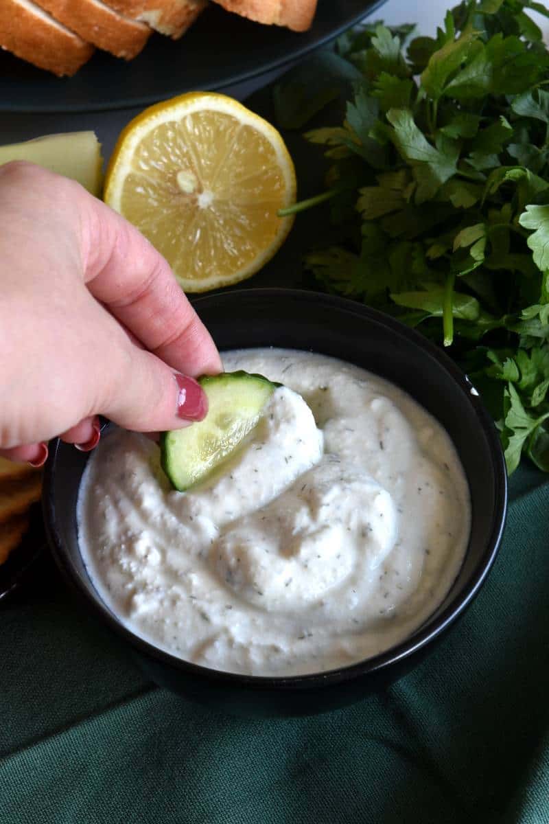 Cottage cheese dip with a cucumber slice being dipped.