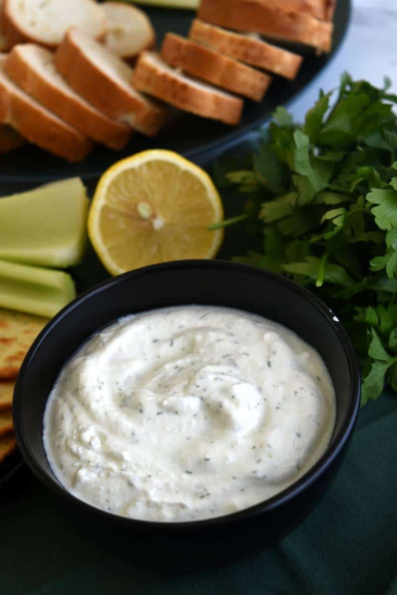 Dip with cottage cheese with bread and vegetables in the background.