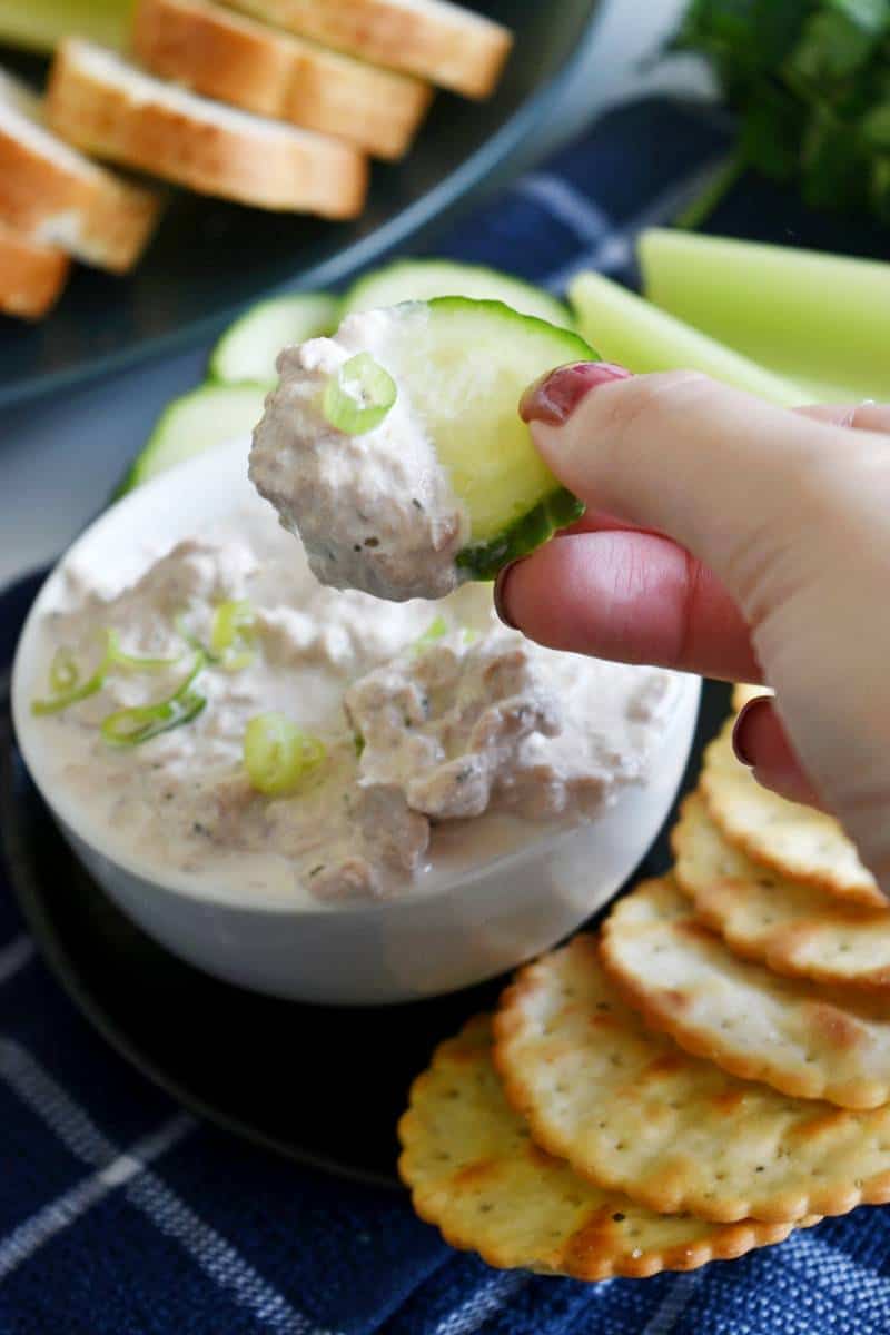 Cucucmber slices dipping into tuna dip.