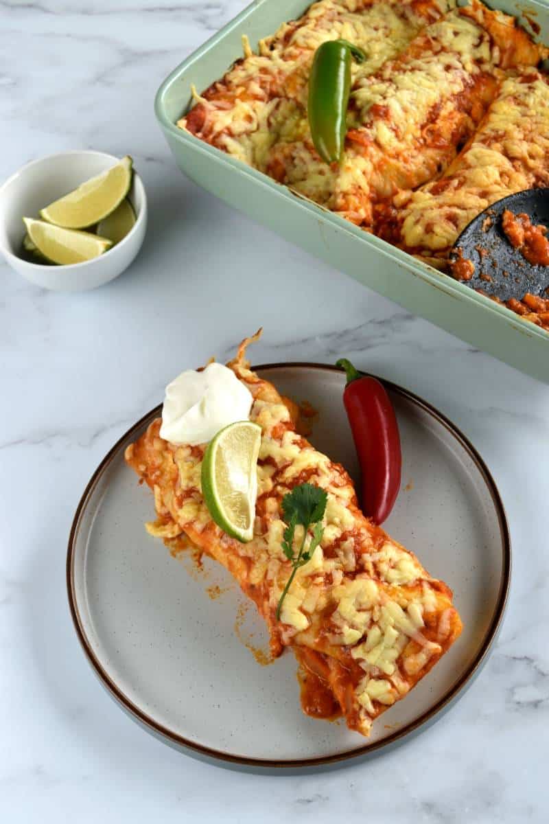 Enchiladas with ground turkey on a plate with a casserole dish on the side.