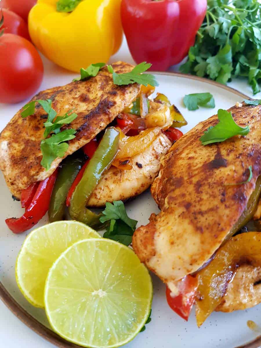 Fajita stuffed chicken on a plate with lime slices.