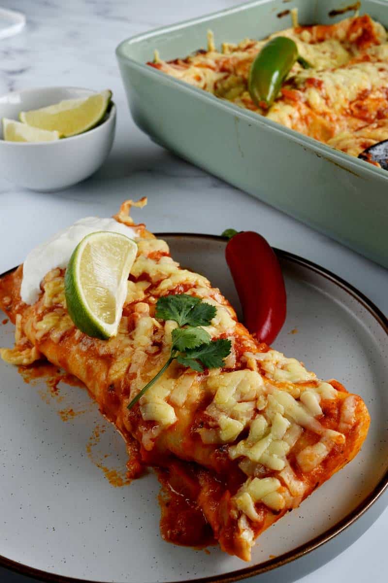 Ground turkey enchiladas on a plate, topped with lime and cilantro.