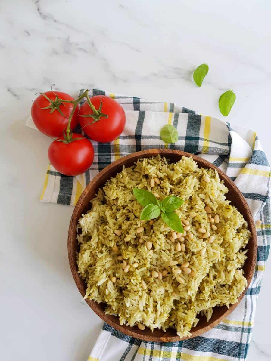 Rice with pesto in a bowl with tomatoes on the side.