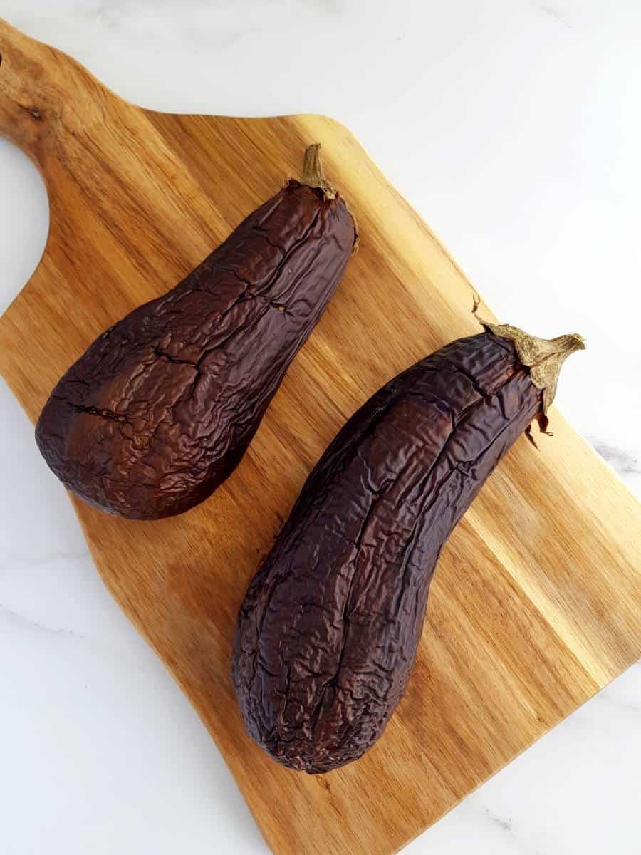 Roasted eggplants on a wooden board.