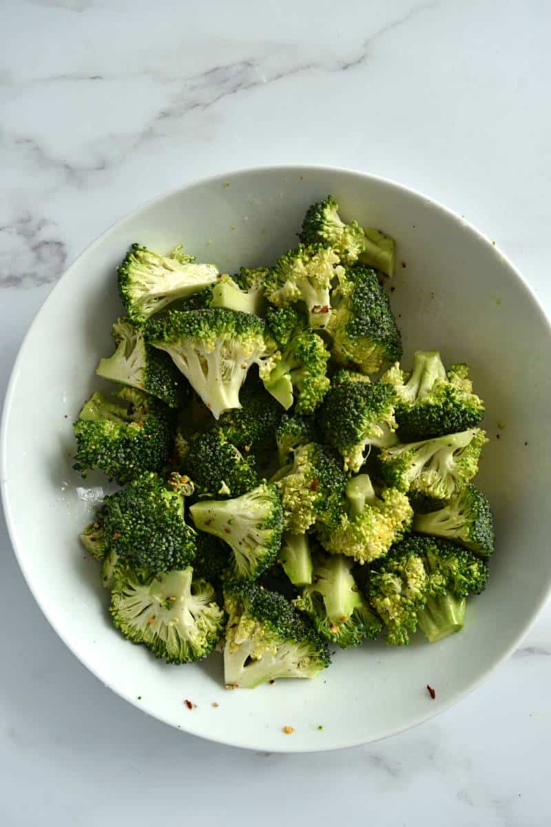 Seasoned broccoli florets in a bowl.