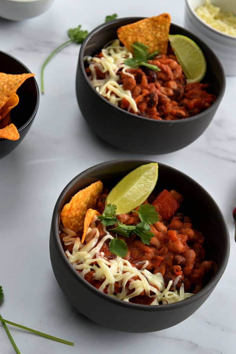 Vegetarian chilli with beans, lime, tortilla chips, cilantro and cheese.