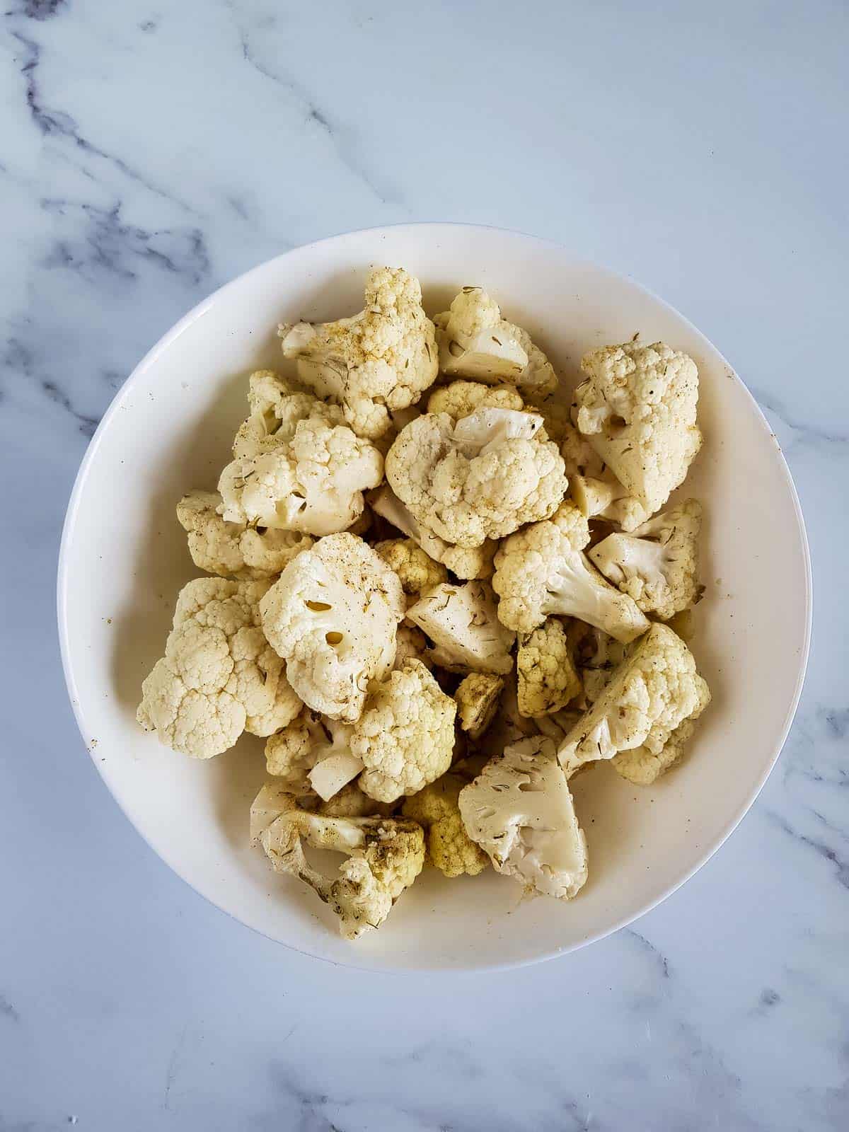 Seasoned cauliflower florets in a bowl.