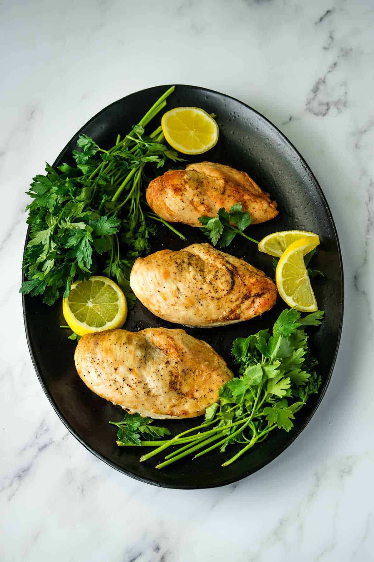 Air fryer chicken breast with cilantro and lemon on a plate.