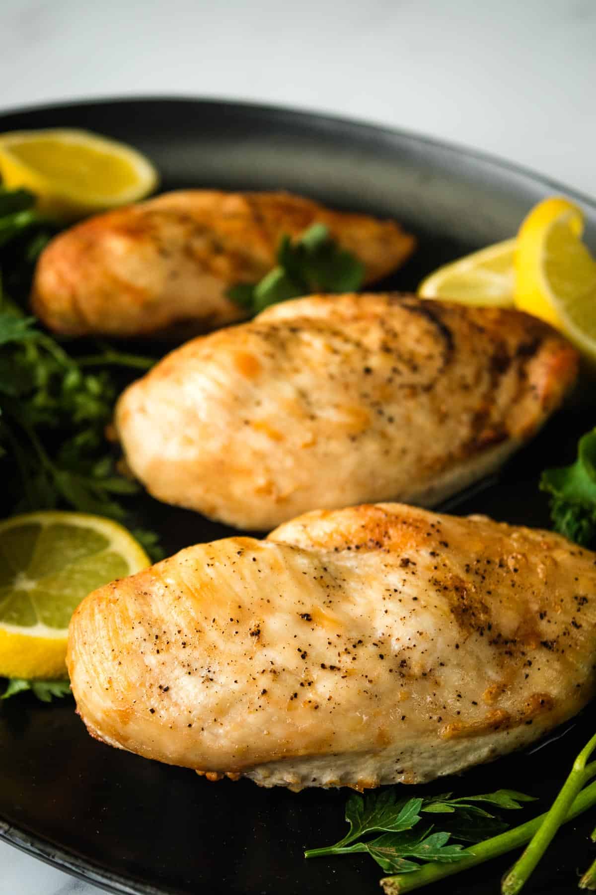 Juicy chicken breasts on a plate with parsley.