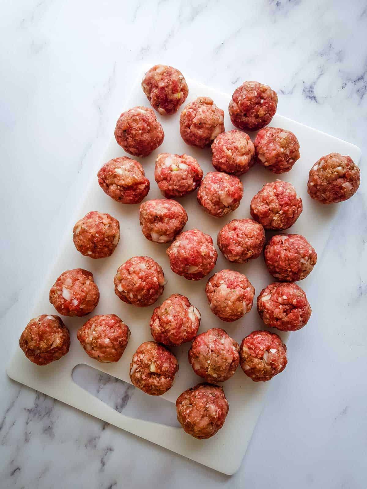 Raw meatballs on a board.