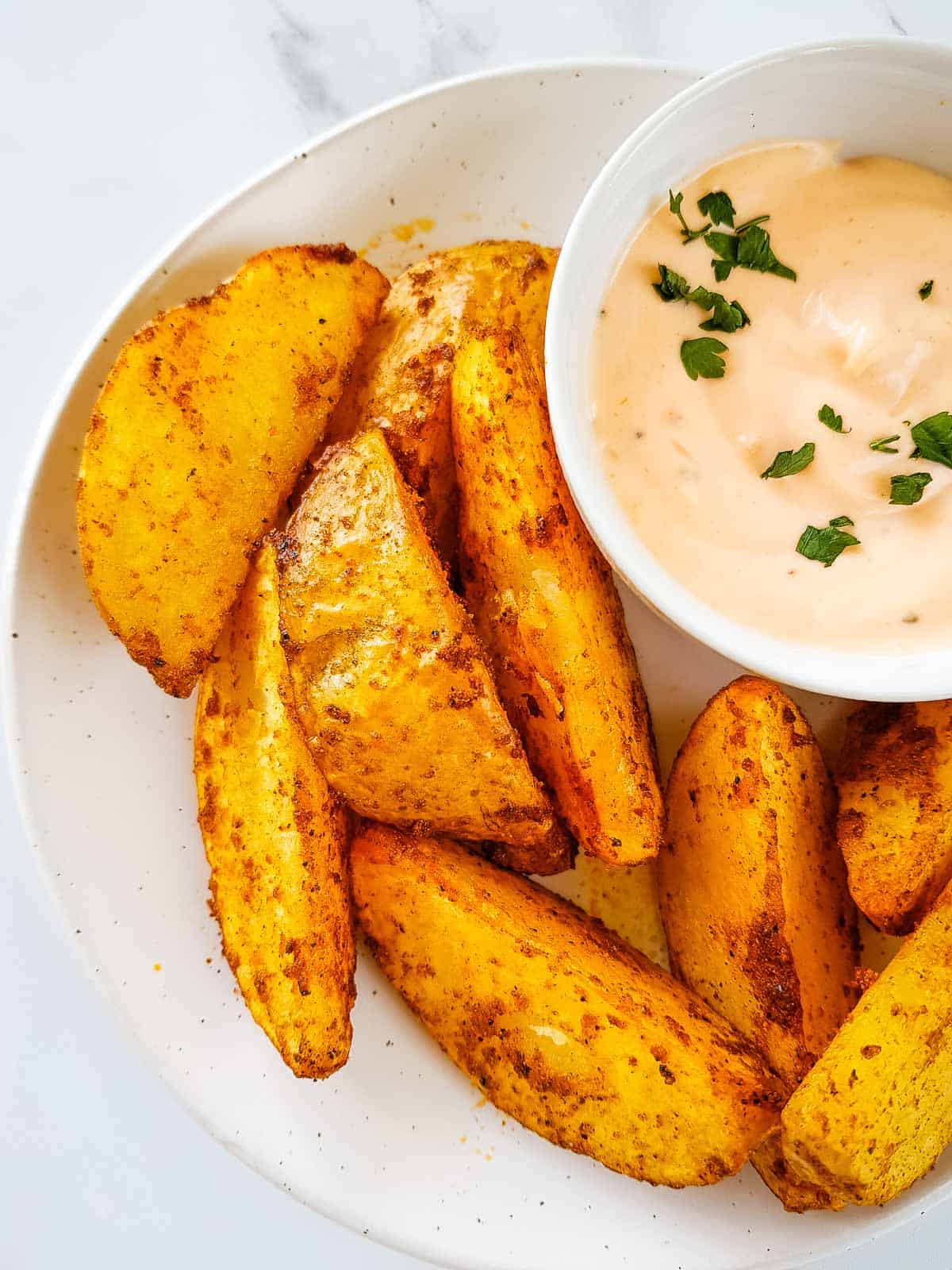 Air fryer potato wedges on a plate with dip.