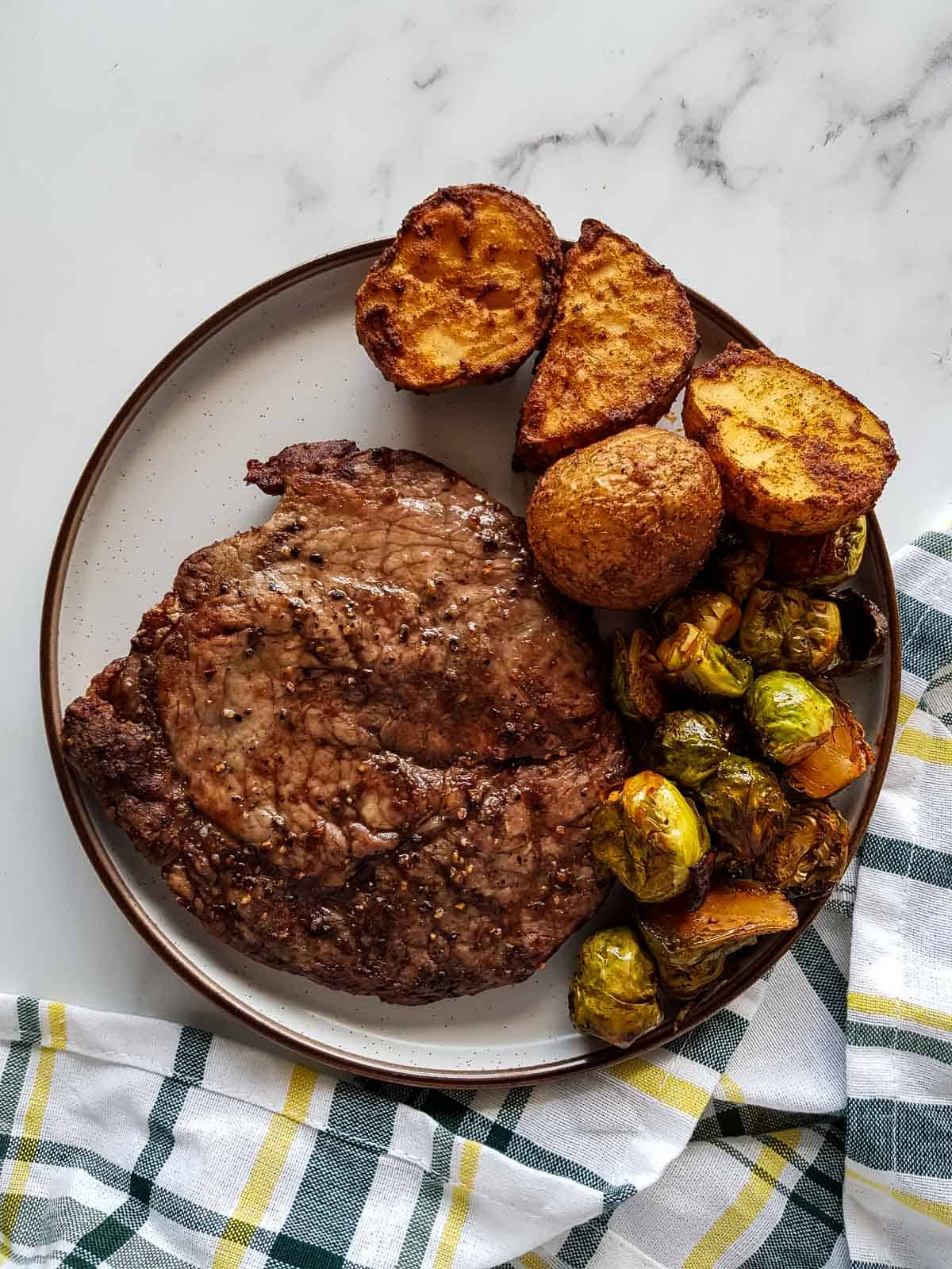 Steak on a plate with brussels sprouts and potatoes.