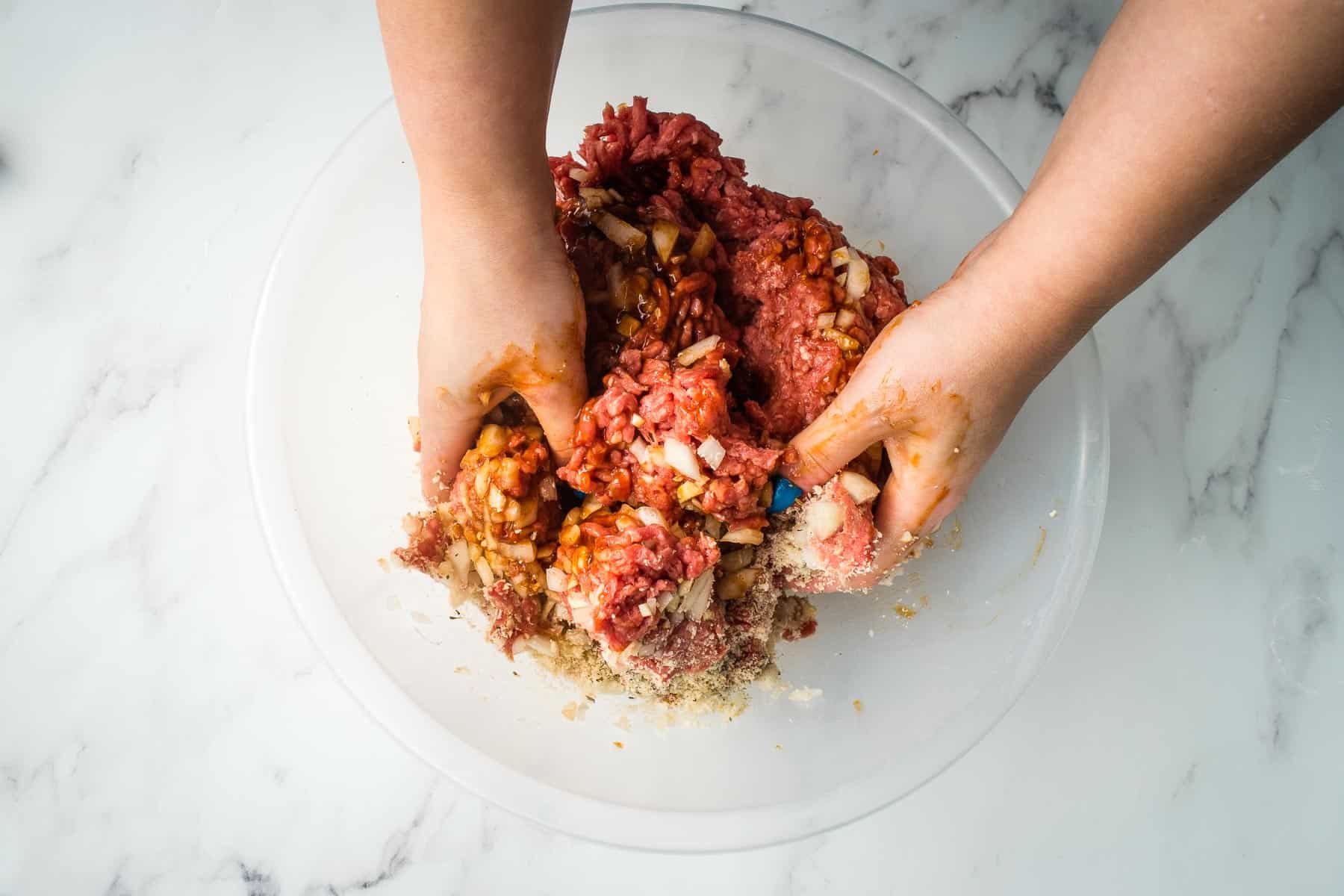 Hands combining ingredients in a bowl.