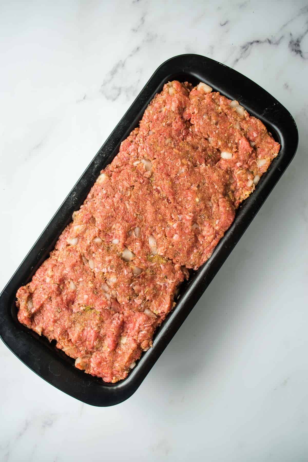 Ground beef mixture in a loaf pan.