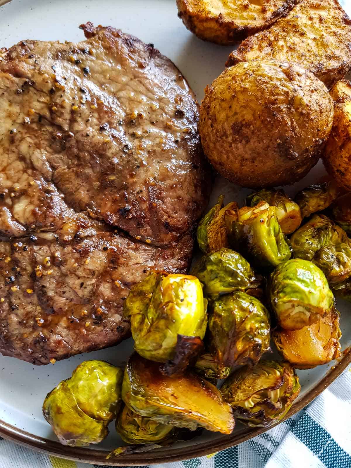 Brussels sprouts on a plate with steak and potatoes.