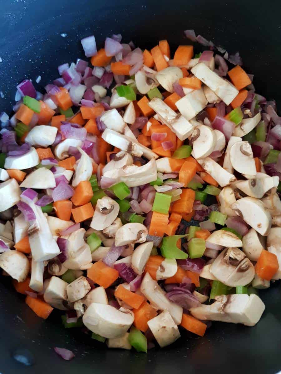 Mushrooms, celery, onion and carrot in a pot.