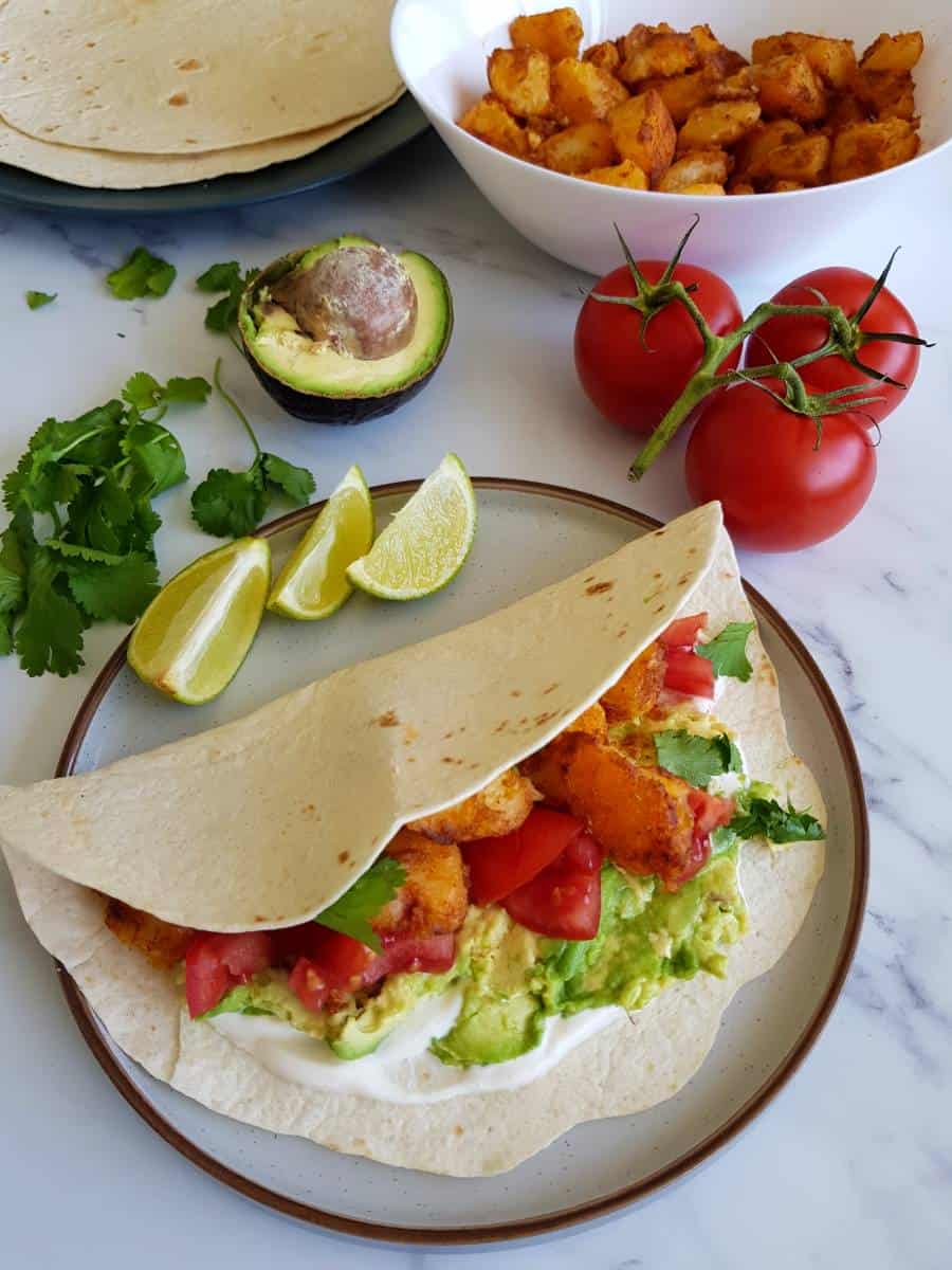 Potato tacos with lime, tomatoes, and guacamole.