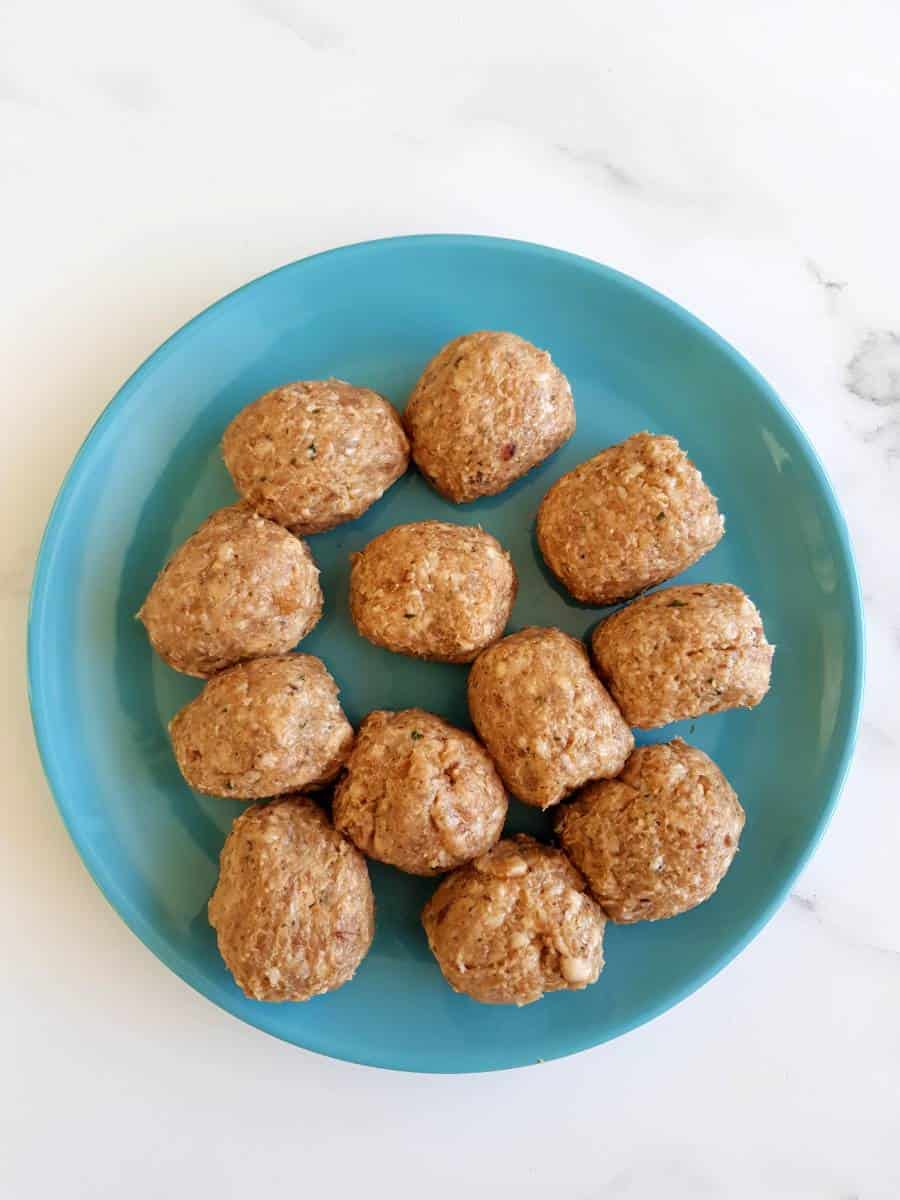 Raw sausage meatballs on a plate.