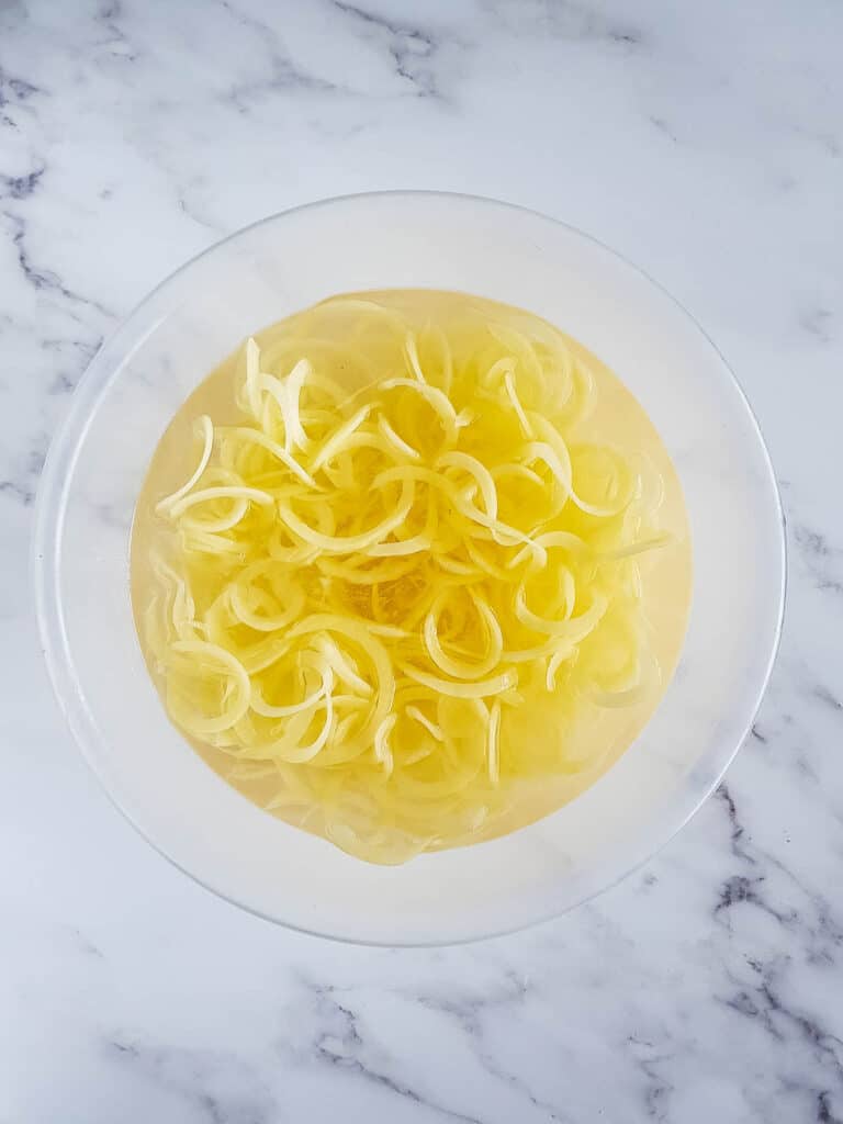Spiralized potatoes in water.