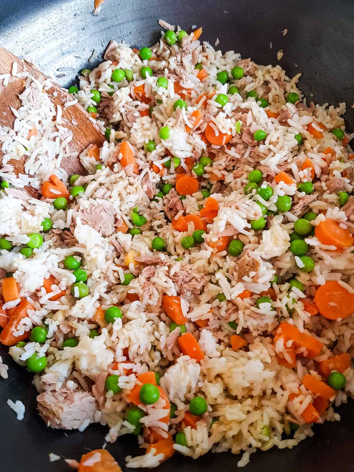 Fried rice with carrots, peas and tuna in a wok.