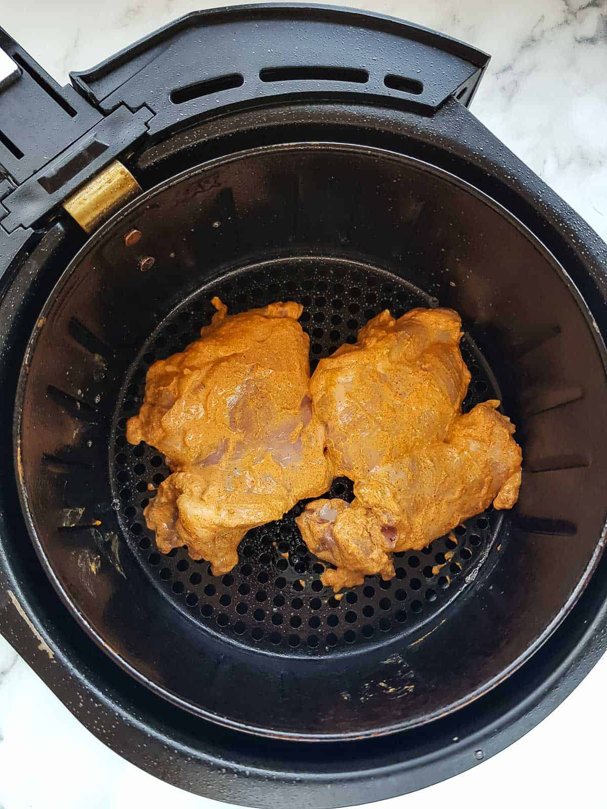 Marinated chicken thighs in an air fryer.