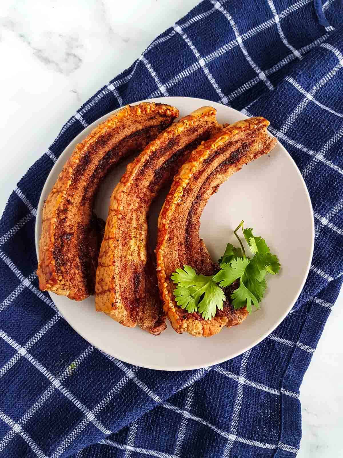 Crispy sliced pork belly with crackling on a plate.