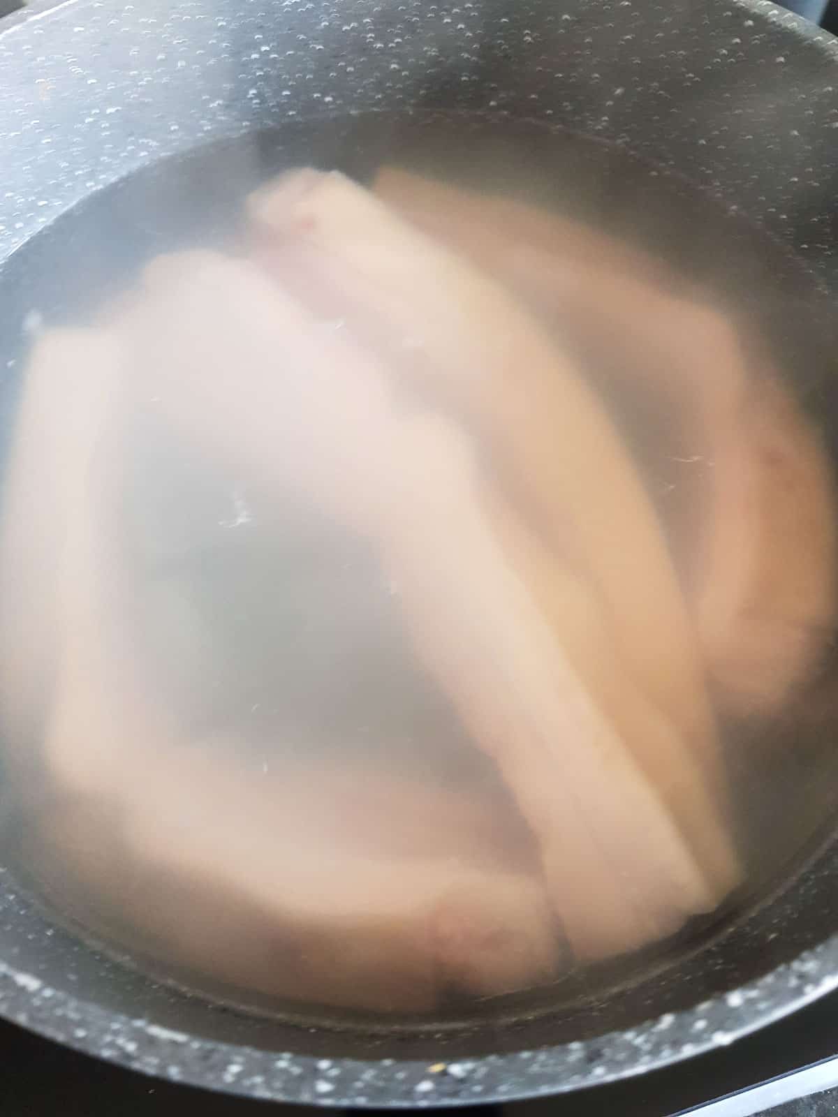 Pork belly boiling in a pot.