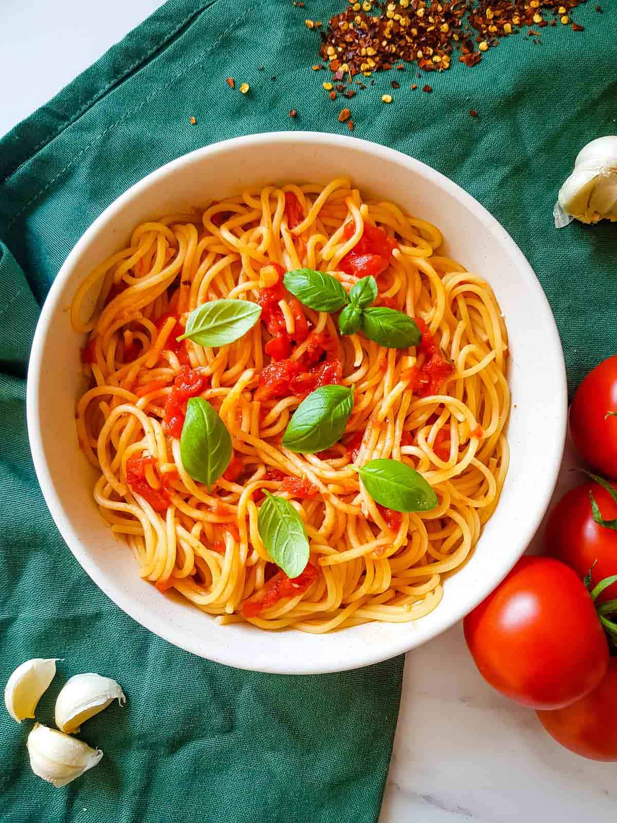 Arrabbiata spaghetti in a bowl with basil leaves on top.