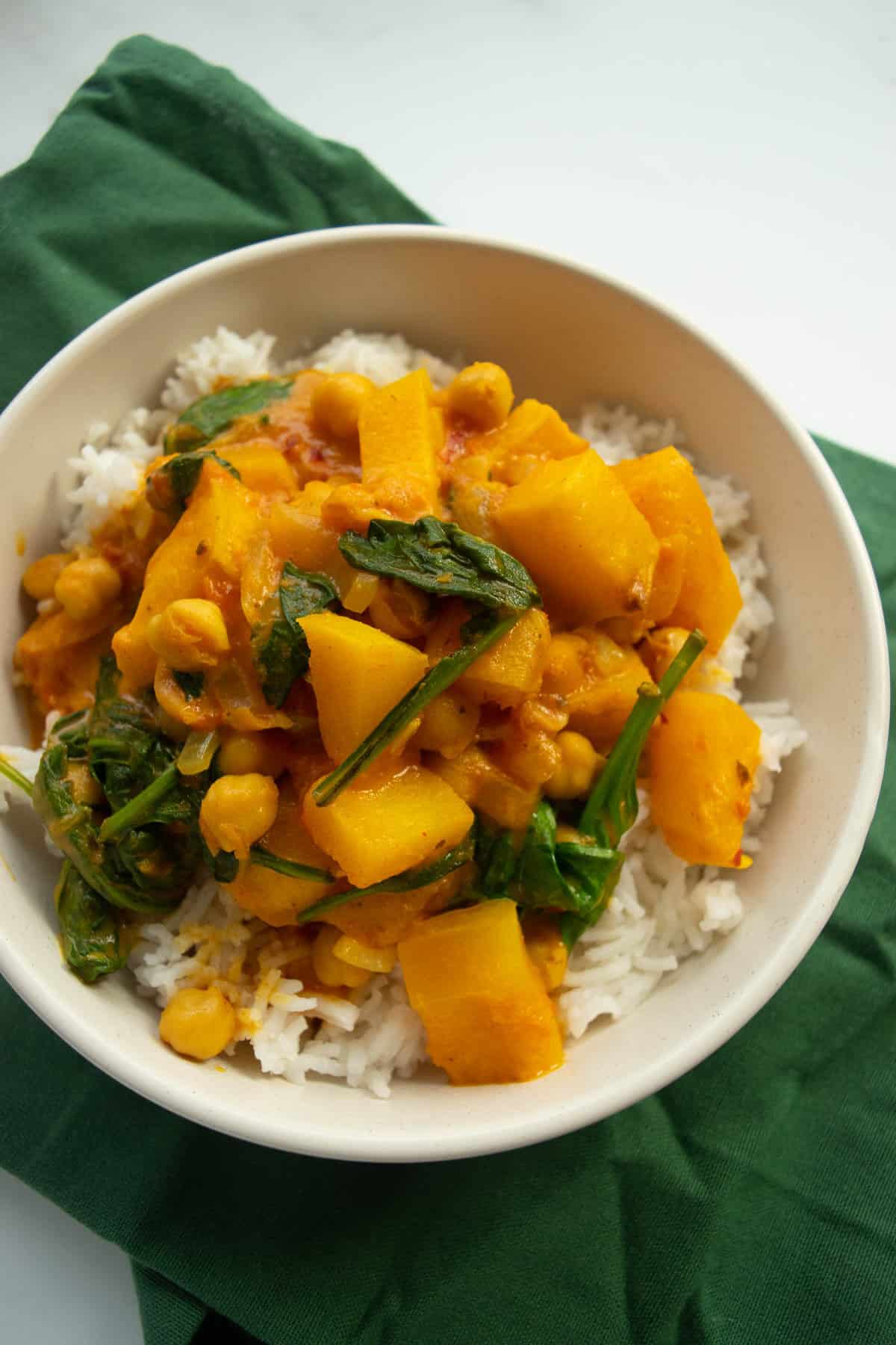 A bowl of curry on a green tablecloth.