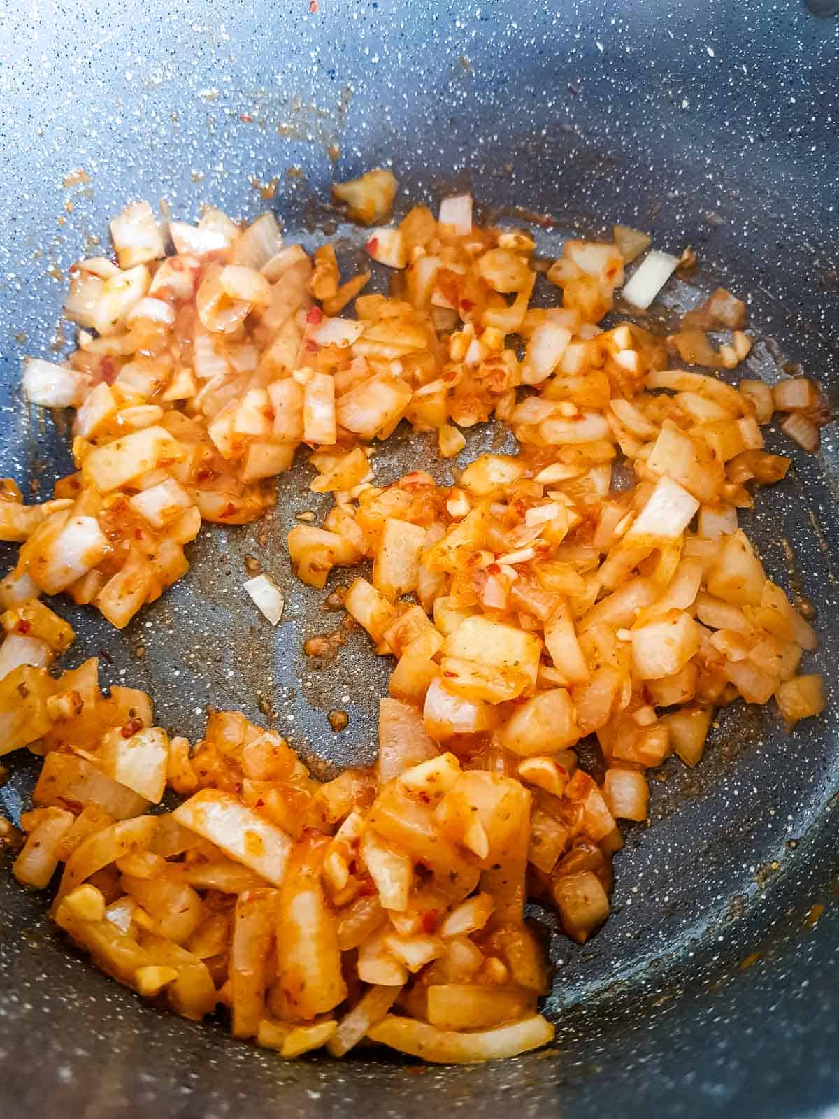 Onions, garlic and curry paste in a pot.