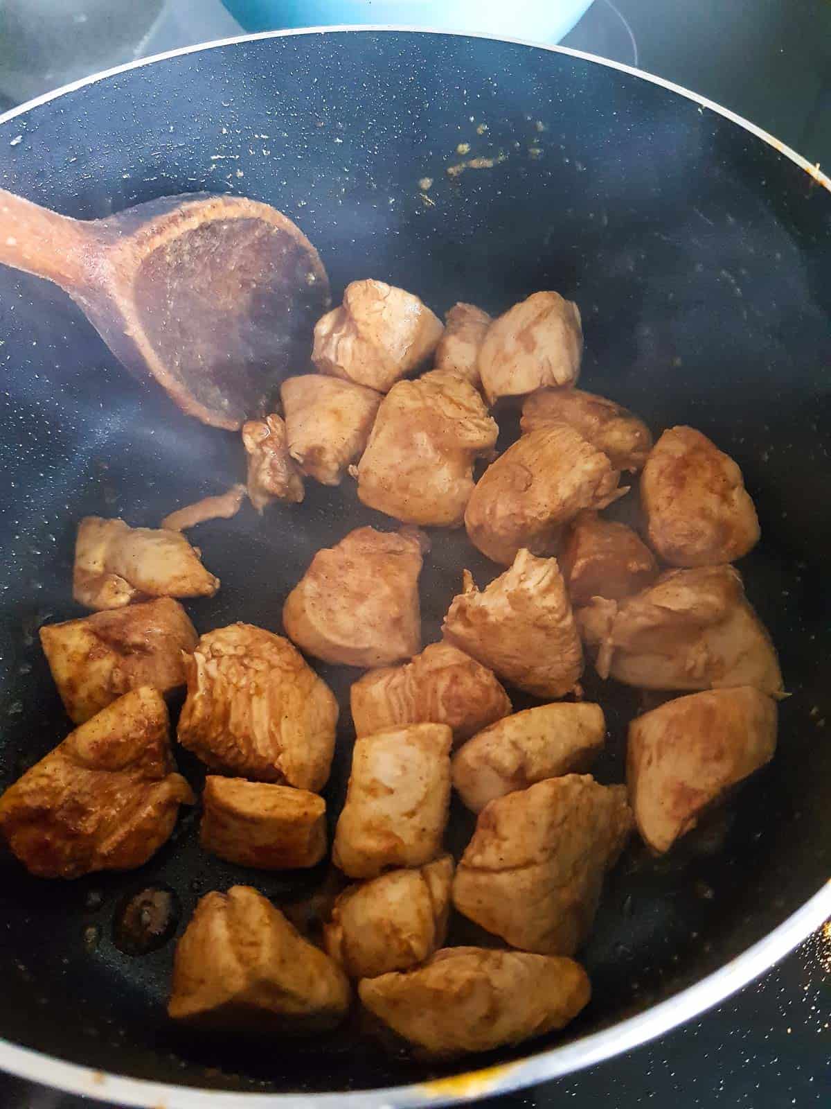 Sauteeing chicken pieces in a pot.